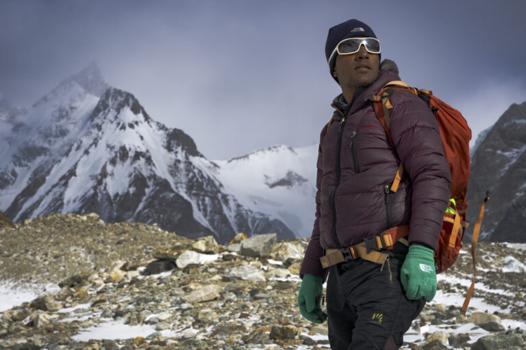 Sajid Sadpara, medium shot with peaks in the background outside K2 basecamp