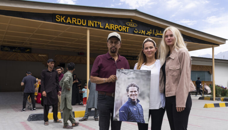 Family members holding a framed portrait of John Snorri outside Skardu International Airport, Summer 2022